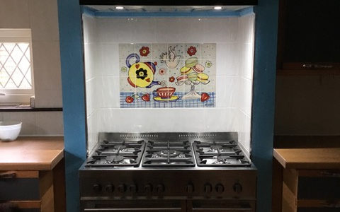 Afternoon tea tile mural behind range cooker in kitchen