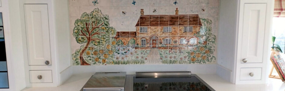 Hand painted tile mural of house and tree behind range cooker